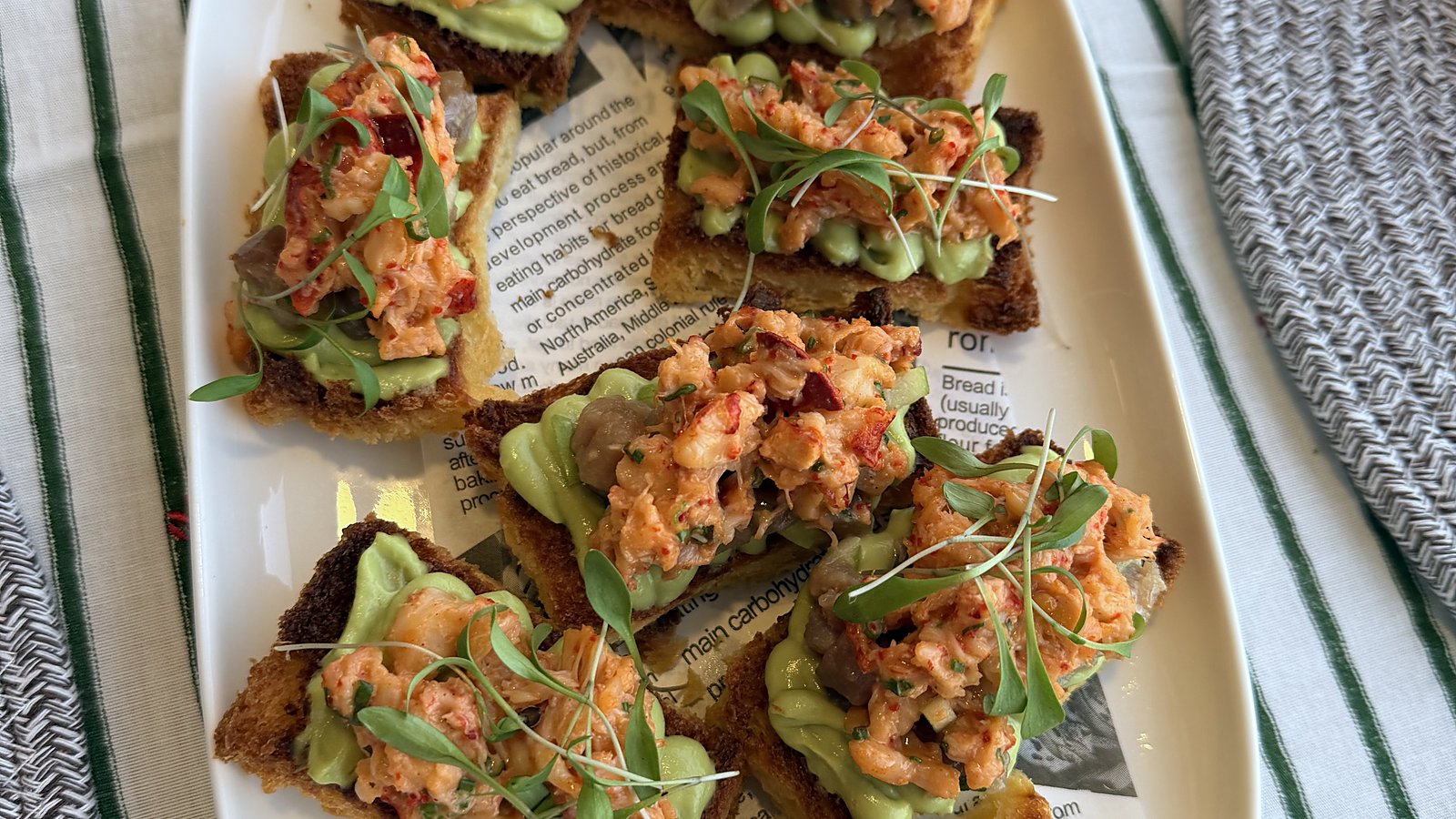 Toasts with avocado and prawn tartare on a long plate