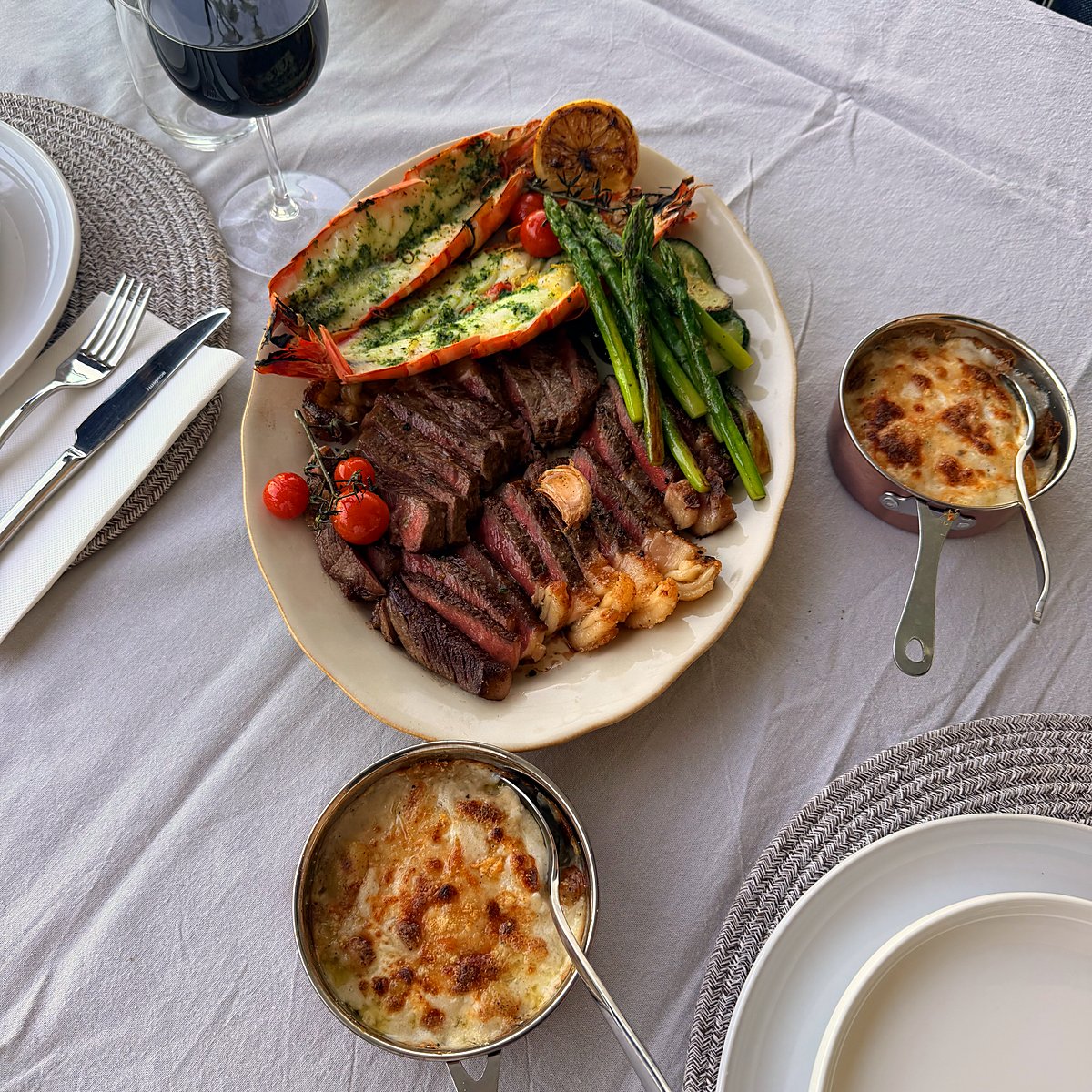 Sliced steak, lobster tails and asparagus with gratins