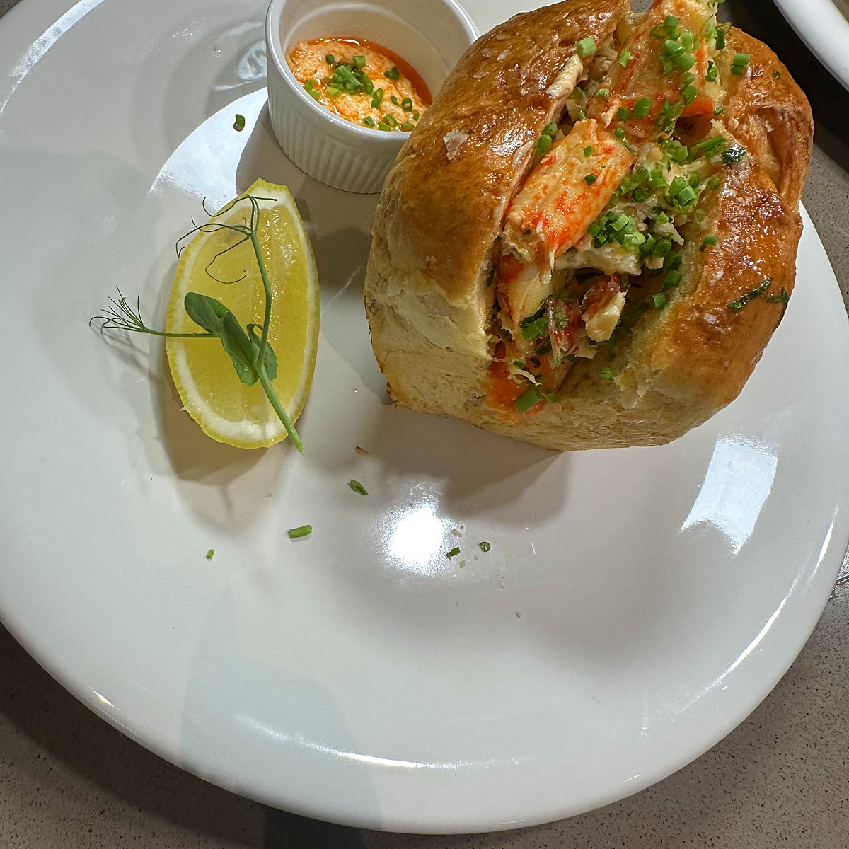 A filled bread roll with a dip and lemon