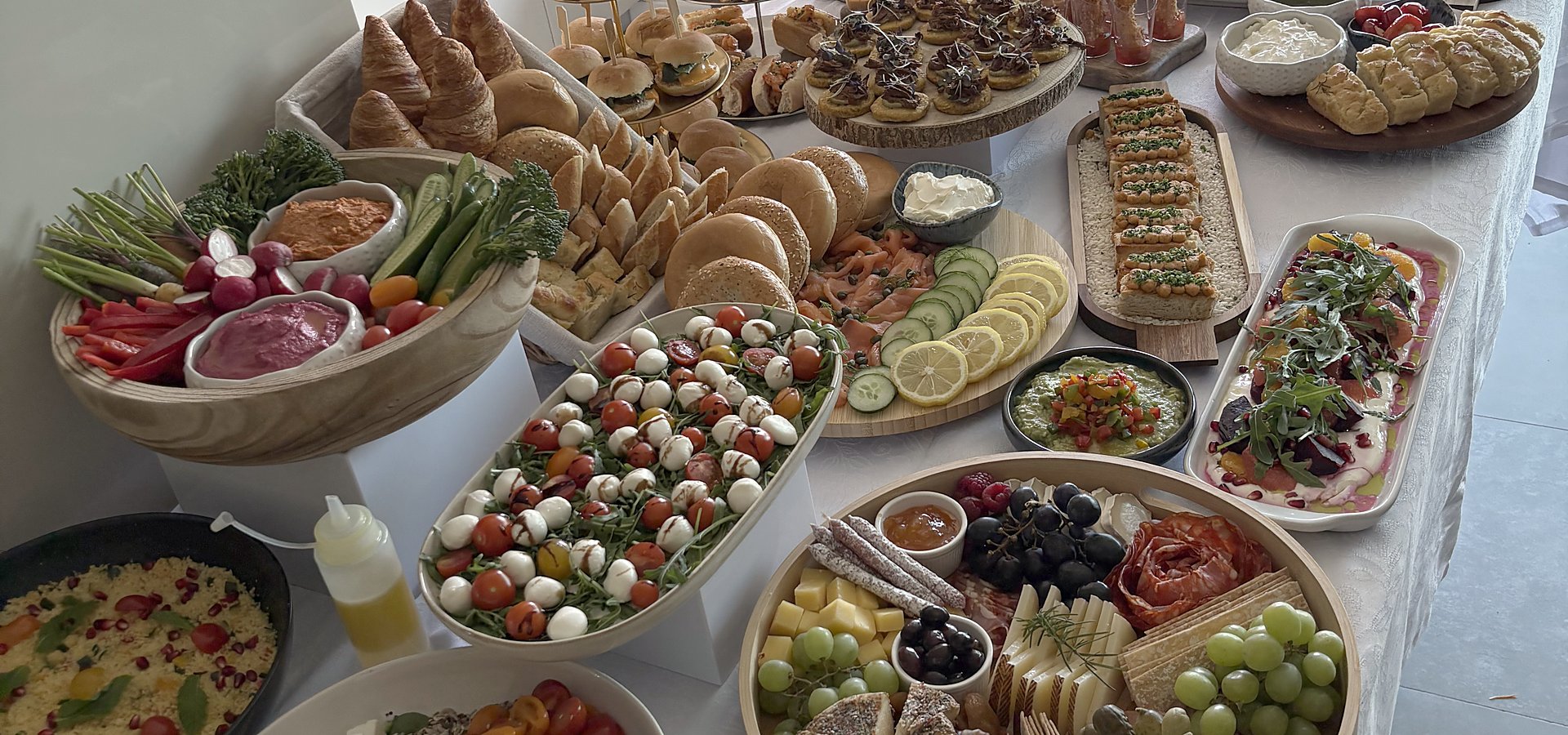 A long buffet table with salads, platters and fresh bread in a villa